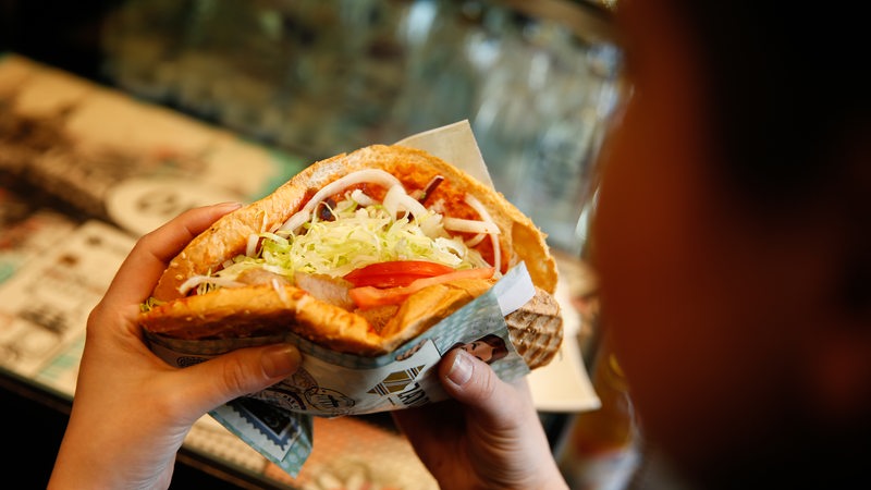 Eine Frau hält einen Döner Kebab in der Hand