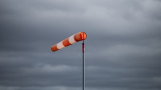 Ein Windsack weht während eines stürmischen Tages vor dunklen Wolken.