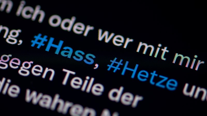 Auf dem Bildschirm eines Smartphones sieht man die Hashtags Hass und Hetze in einem Twitter-Post. 