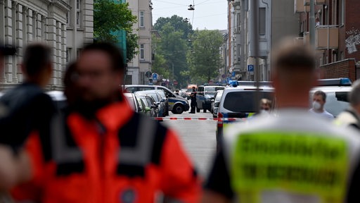 Personen in Uniform stehen vor einer abgesperrten Straße.