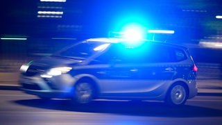 Ein Polizeiauto mit Blaulicht fährt auf einer Straße.