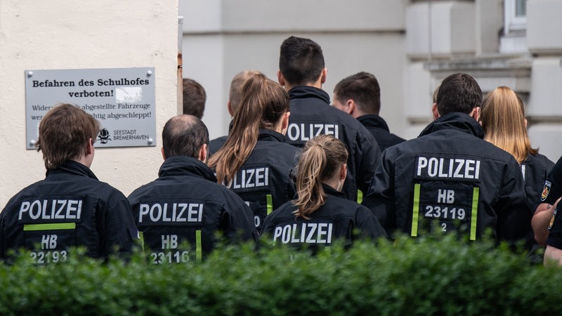 Einsatzkräfte der Polizei betreten eine Schule. 