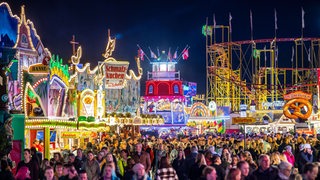 Die Fahrgeschäfte auf dem Bremer Freimarkt auf der Bürgerweide leuchten mit bunten Lichtern und Reklameschriftzügen.