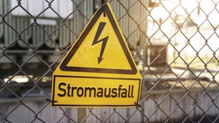 Schild an einem Zaun mit der Aufschrift Stromausfall