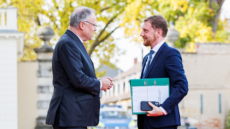 Die Ministerpräsidenten Weil und Kretschmer sprechen miteinander.