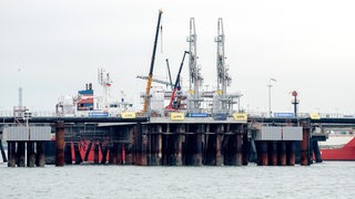 Technische Anlagen und ein Kran stehen auf dem Anleger für das LNG-Terminal in der Nordsee vor Wilhelmshaven.