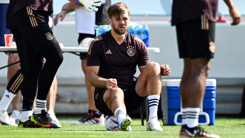 Niclas Füllkrug sitzt im Training beim DFB auf einem Ball.