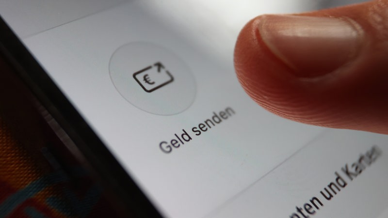 Display eines Smartphones mit der Aufschrift Geld senden. Eine Finger.