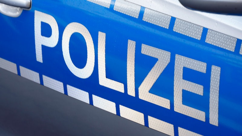 Polizei steht auf der Tür eines Autos. 