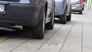 Autos parken auf einem Gehweg.