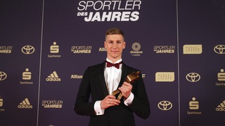 Schwimm-Olympiasieger Florian Wellbrock posiert im Smoking mit seiner Trophäe bei der Sportler-des-Jahres-Gala.