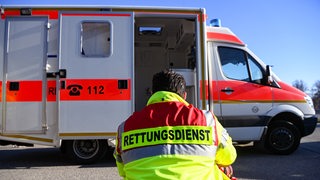 Mann sitzt vor Rettungswagen