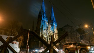 Blau-gelb erleuchtete St. Nicholas Kirche hinter Krieg-Barrieren in Kiew