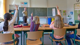 Schüler in der Grundschule melden sich im Unterricht. 