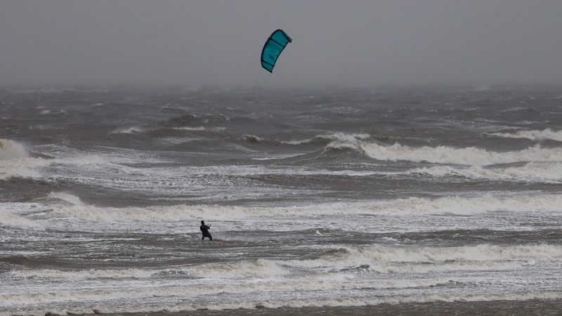 Ein Kitesurfer nutzt die Orkanböen für ein Rennen auf dem Wasser.