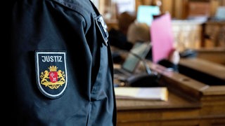 Zwei Angeklagte sitzen vor Prozessbeginn im Gerichtssaal. Drei Männern wird vorgeworfen, im April 2020 einen Mann getötet zu haben. 