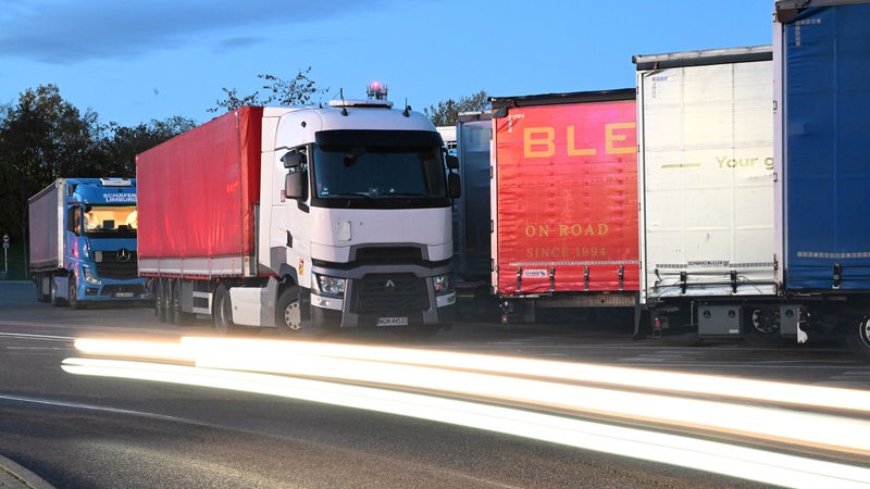 Lastwagen stehen am Abend auf einem Rastplatz.