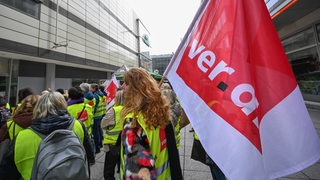 Mitarbeiter des insolventen Kaufhaus-Konzerns Galeria Karstadt Kaufhof stehen mit Westen und Fahnen der Gewerkschaft Verdi bei einem Warnstreik vor dem Gebäude von Galeria Kaufhof.