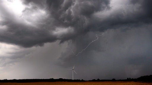 Dunkle Gewitterwolken über einem Windrad.