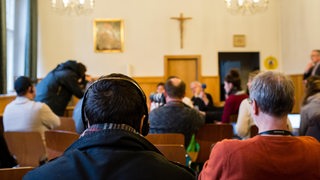 Ein Flüchtling hört sich am 21.03.2016 die Übersetzung eines Pressegespräches zu christlichen Flüchtlingen und ihrer Unterbringung in der katholischen Kirche St. Elisabeth in Berlin, in Arabisch über Kopfhörer an.