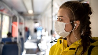 Eine Frau mit einer Schutzmaske steht in einer Bremer Straßenbahn.