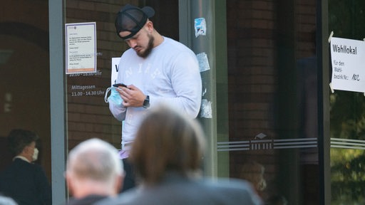 Junge Wähler und Wählerinnen warten vor einem Wahllokal