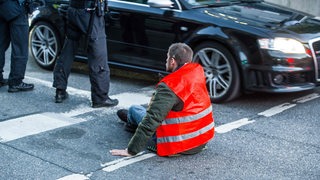 Protestler der "Letzten Generation" sitzt festgeklebt auf einer Straße in München (Arhcivbild)