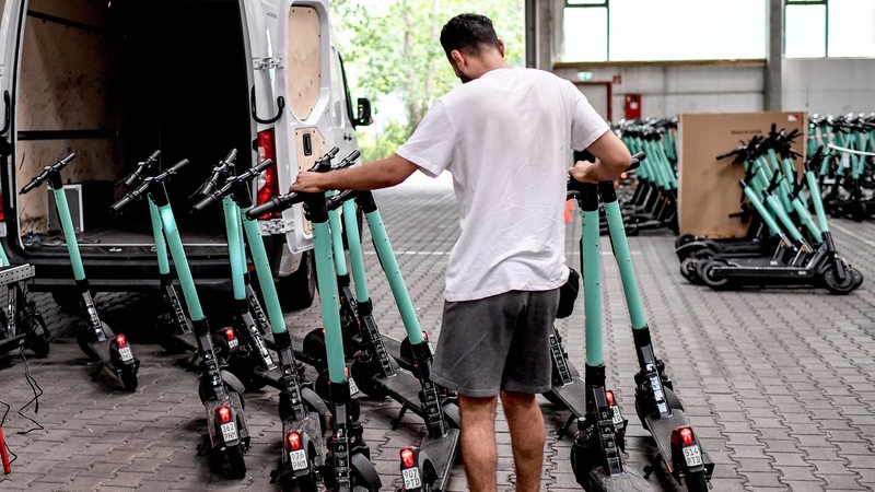 Ein Mitarbeiter lädt E-Scooter des Anbieters Tier in einen Transporter.