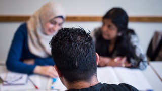 Drei Schüler nehmen in einer Volkshochschule an einem Integrationskurs teil