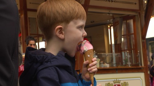 Ein Kind isst ein Eis von einem Stand des Bremer Freimarkts auf dem Marktplatz.