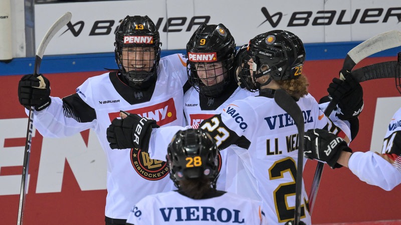 Die Eishockey-Spielerinnen der deutschen Nationalmannschaft liegen sich nach einem Treffer jubelnd in den Armen.