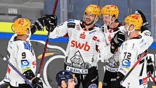 Eishockey-Spieler der Fischtown Pinguins kommen auf dem Eis zum Jubel zusammen nach einem Treffer gegen Bratislava.