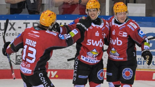 Die Eishockey-Spieler Ross Mauermann und Ziga Jeglic bejubeln mit Torschützen Fabian Herrmann dessen ersten Treffer in der DEL.