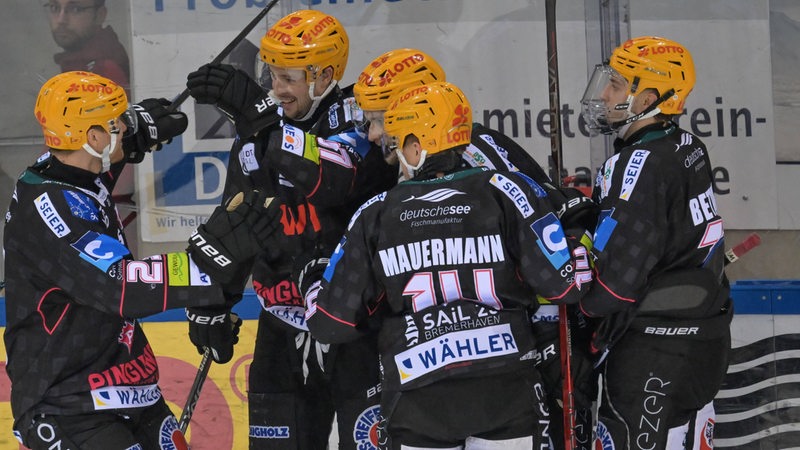 Eishockey-Spieler der Fischtown Pinguins kommen auf dem Eis zusammen und bejubeln einen Treffer.