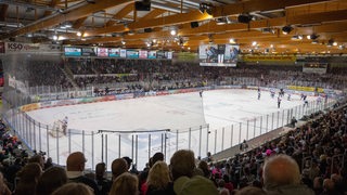 Der Innenraum der Eisarena Bremerhaven. Auf dem Eis stehen die Spieler, auf den Rängen sitzen die Zuschauer.