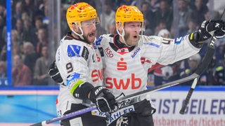 Die Eishockey-Spieler Jan Urbas und Nicholas Jensen von den Fischtown Pinguins liegen sich jubelnd in den Armen nach einem Treffer im Finale.