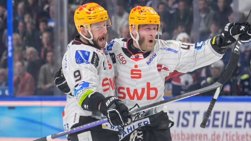 Die Eishockey-Spieler Jan Urbas und Nicholas Jensen von den Fischtown Pinguins liegen sich jubelnd in den Armen nach einem Treffer im Finale.