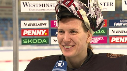 Die Eishockey-Torhüterin Sandra Abstreiter strahlt bei einem Interview in der Eisarena Bremerhaven.