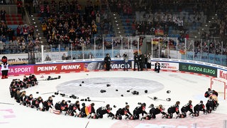 Die deutschen Eishockey-Spielerinnen feiern in der Eisarena Bremerhaven ihre Olympia-Qualifikation rutschen kniend hintereinander auf dem Eis im Kreis, wie ein Zug.