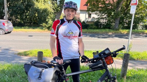 Ein Fan der Fischtown Pinguins steht in Bremerhaven abfahrbereit an seinem Fahrrad vor der Tour nach Straubing.