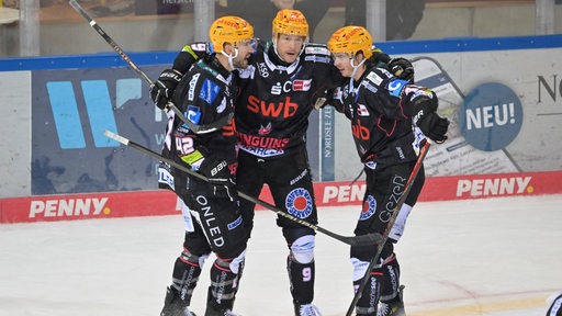 Eishockey-Spieler der Fischtown Pinguins, Jan Urbas, Matthew Abt und Ziga Jeglic, umarmen sich auf dem Eis und bejubeln einen Treffer.