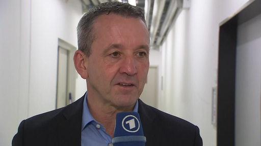 Eishockey-Trainer Thomas Popiesch von den Fischtown Pinguins steht vor der Kabine beim Interview.