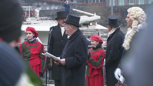 Am Osterdeich stehen mehrere Personen verkleidet für die Eiswett-Tradition.