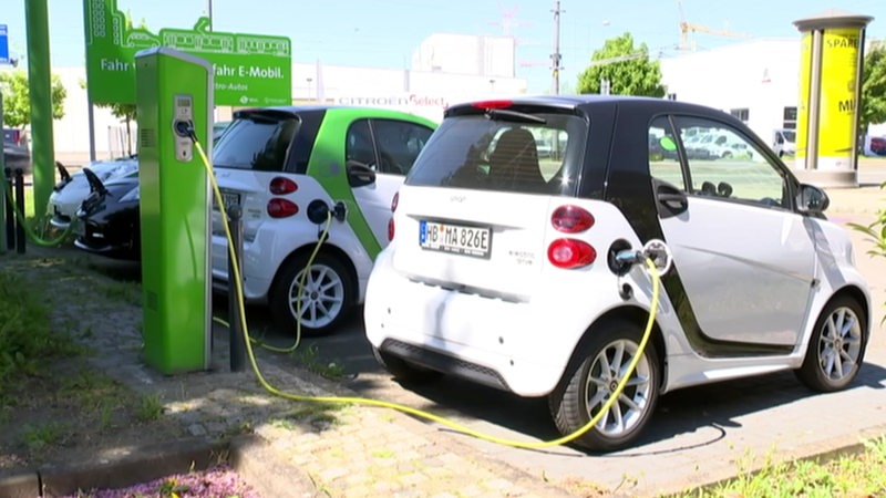 Zwei Elektroautos, die an einer Säule mit einem Kabel aufgeladen werden.