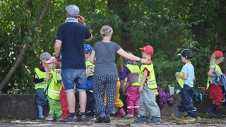 Eine Kindergruppe mit Betreuerin und Betreuer macht einen Ausflug in einen Park.