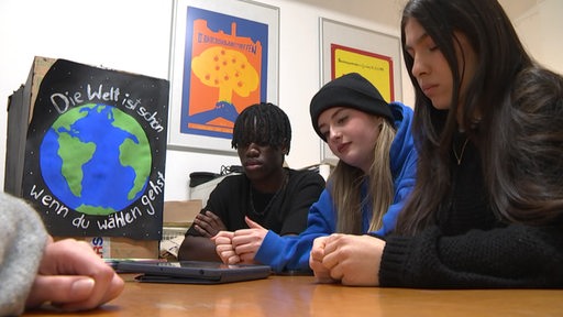 Schülerinnen und Schüler sitzen vor ihrem iPad in einem Klassenraum.