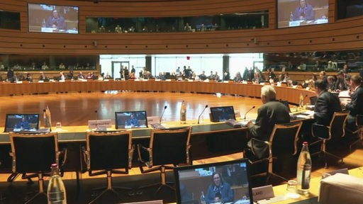 In einem großen Saal sitzen mehrere Politiker bei einem Kongress.