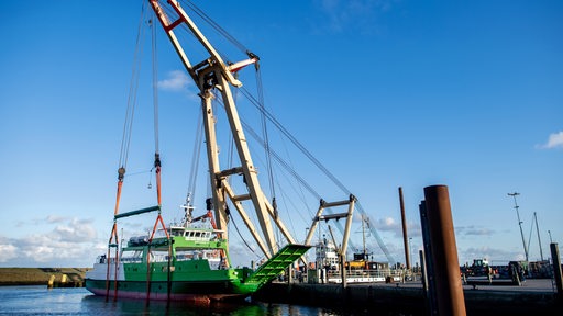 Ein Schiff hängt an einem Kran