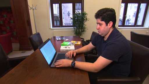 Der Iraner Farhad Movahedi sitzt mit einem Laptop an einem Tisch