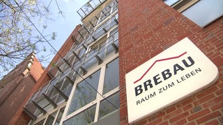 Die Fassade der Brebau, an der ein Schild mit der Aufschrift "Brebau Raum zum Leben" angebracht ist.